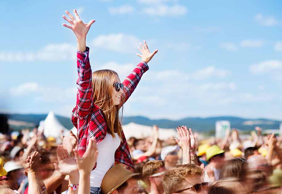 Junge Frau jubelt bei einem Openair-Konzert.